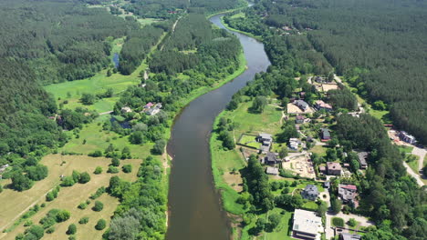 AERIAL:-High-Altitude-Flight-Over-River-Bank-with-Forest-and-Houses-on-Each-Side-of-River