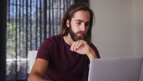 Caucasian-man-calculating-finances-and-using-laptop-at-home