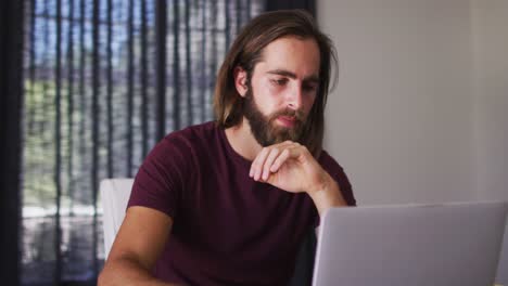 hombre caucásico calculando las finanzas y usando computadora portátil en casa