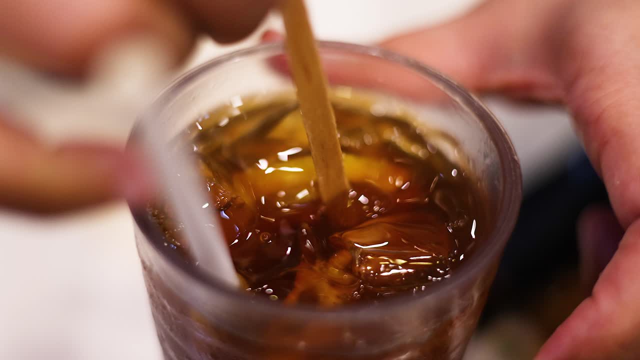 Mani che mescolano tè freddo con una fetta di limone