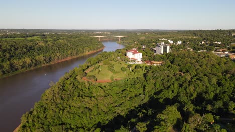 Luftaufnahme-Des-Iguazu-Flusses-Mit-Der-Brücke-Zwischen-Argentinien-Und-Brasilien-Im-Hintergrund