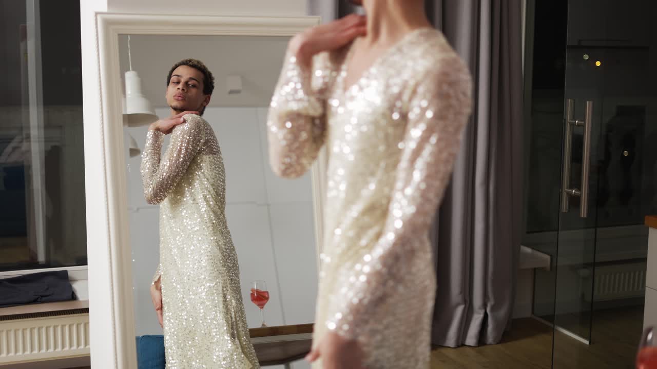 드레스를 입은 감각적인 남자가 거울 앞에 서서 자신을 존경합니다. 슬로우 모션