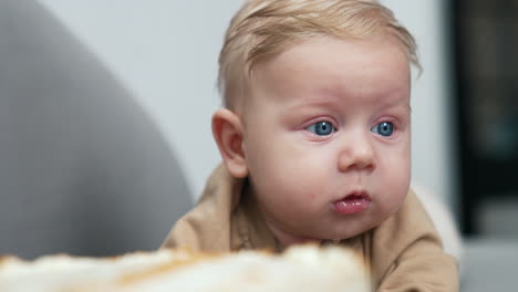 face of a lovely caucasian baby boy with fair hair. cute child portrait with big blue eyes. close up. blurred backdrop.
