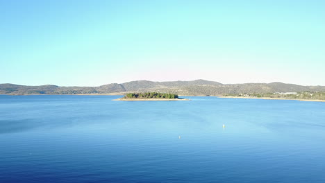 panorama of blue calm lake with mountainscape in background near jindabyne village, new south wales, australia