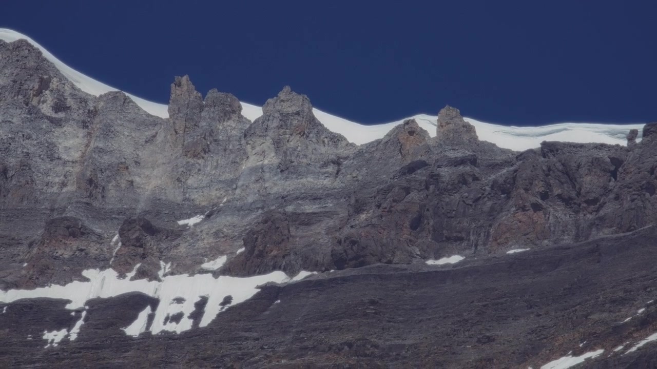 Cime montuose rocciose coperte di neve su sfondo di cielo blu