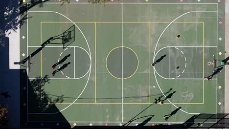 aerial top view of neighbourhood kids playing basketball together in summer light shadows