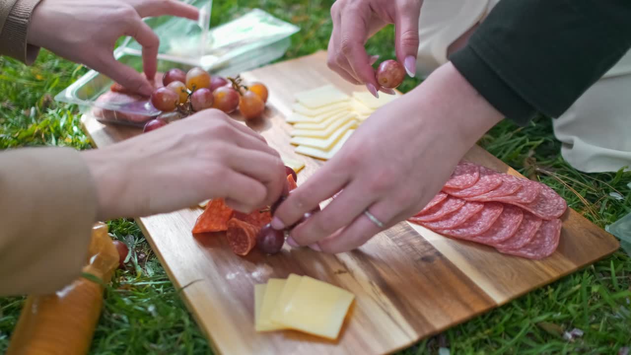 una pareja montando una tabla de charcutería en washington dc en un brillante día soleado en un parque en una tabla de corte de madera