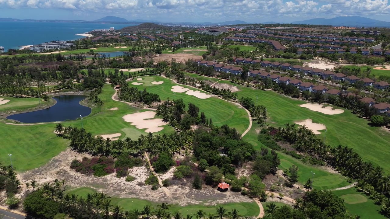 Riprese aeree con drone di un campo da golf panoramico a Mui Ne, Phan Thiet, Vietnam, che mostrano fairway e green curati circondati da vegetazione tropicale e un bellissimo paesaggio costiero nel Sud-est asiatico