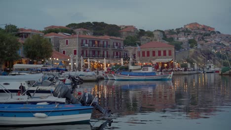 restaurants and cafes (tavernas) around the molyvos marine port, mithymna castle and houses in the background at sunset, lesbos island