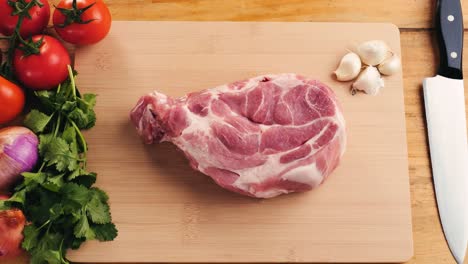 raw pork chops on wooden cutting board with vegetables and garlic