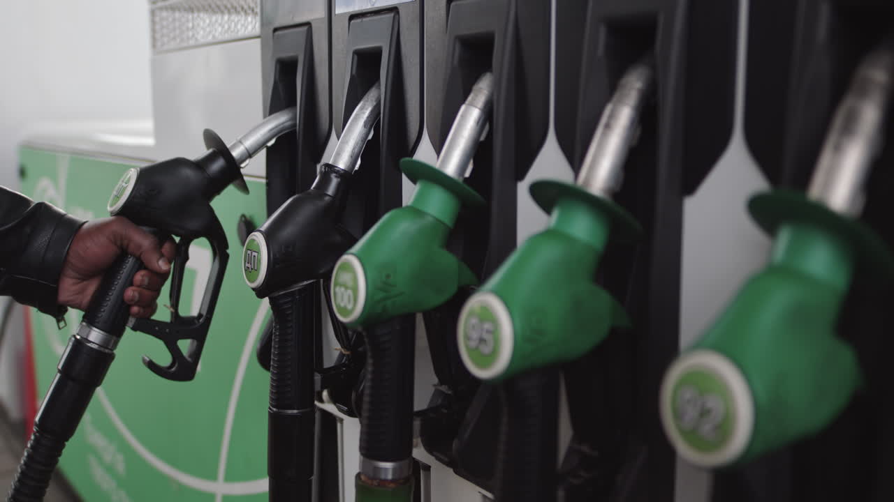 Primo piano di una mano e di una pompa di carburante che viene inserita nella sua posizione in una stazione di servizio