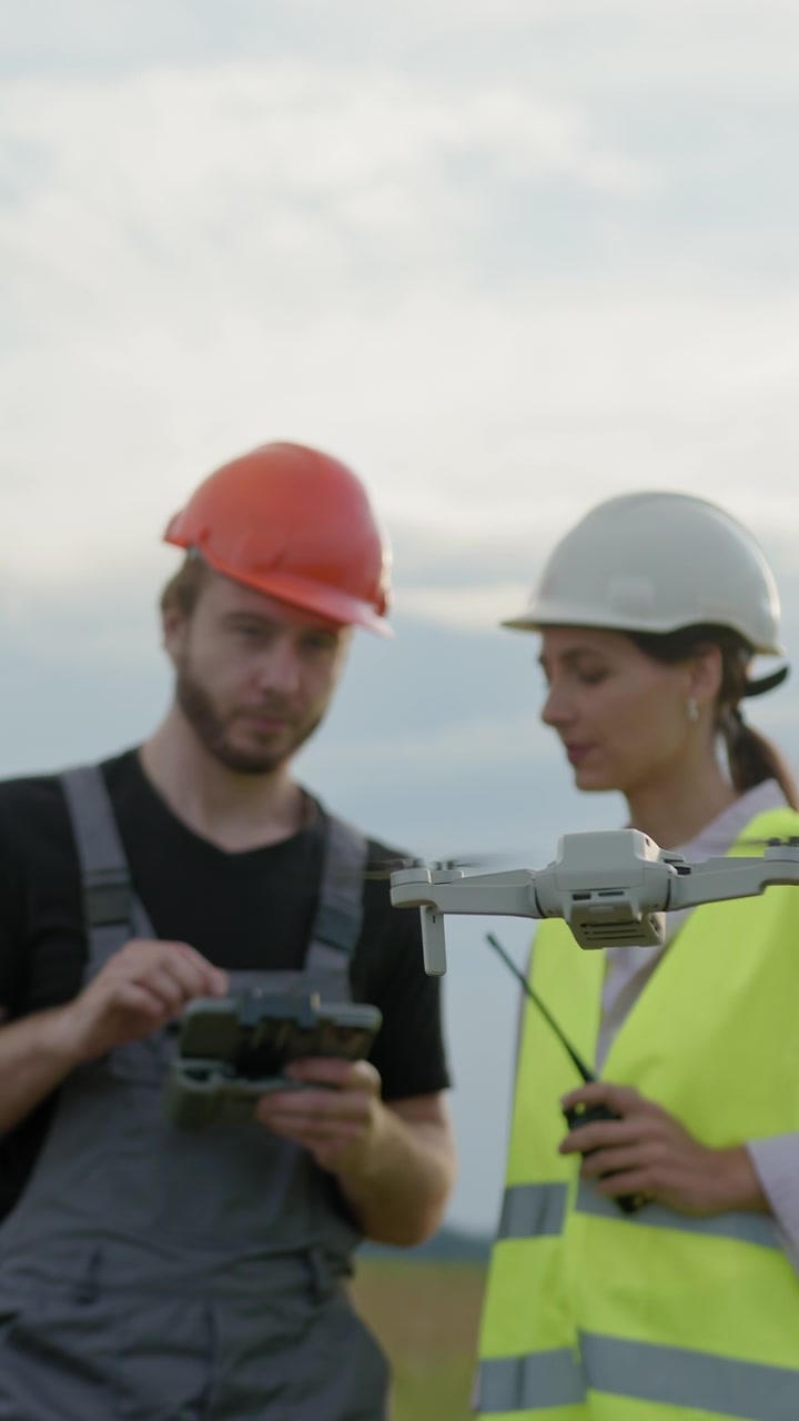 Teknikere i sikkerhedsveste og hatte bruger en drone og radio til inspektion ved en vindmøllepark.