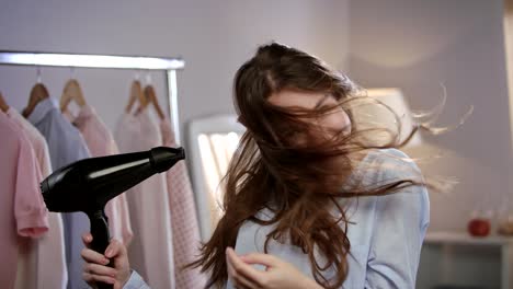 mujer feliz secando el cabello en casa. retrato de mujer morena soplando el cabello