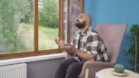 muslim man praying in front of the window.