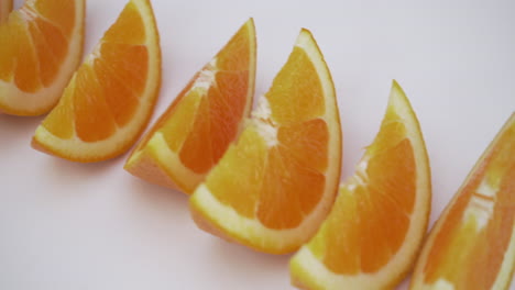 moving shot of orange slices-wedges on white isolated background, healthy food choices