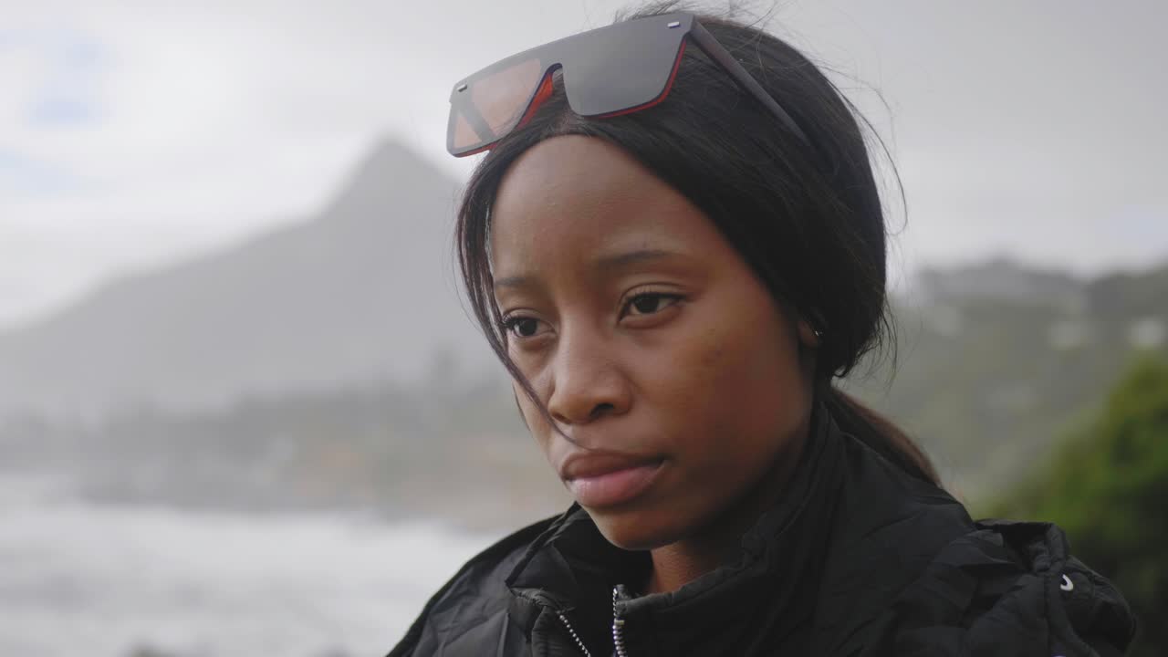 Dissapointed Black Woman on a cloudy day with beach and hill in the back ground