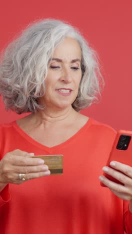 senior woman using smartphone and credit card for online shopping