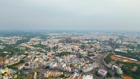 the bustling cityscape of tiruchirappalli with dense buildings and roads and malaikottai rock fort in the background