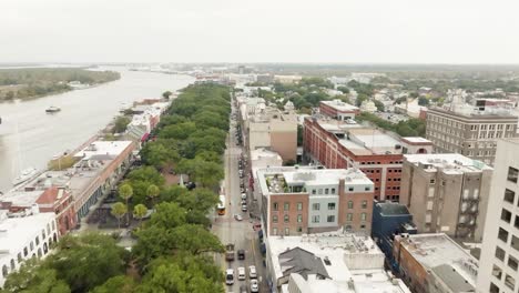 Drone-of-Savannah-Georgia-riverfront-area-along-the-river-with-cars-and-boats-on-an-overcast-day-over-street