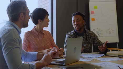 Business-executives-discussing-over-laptop-in-conference-room-4k-