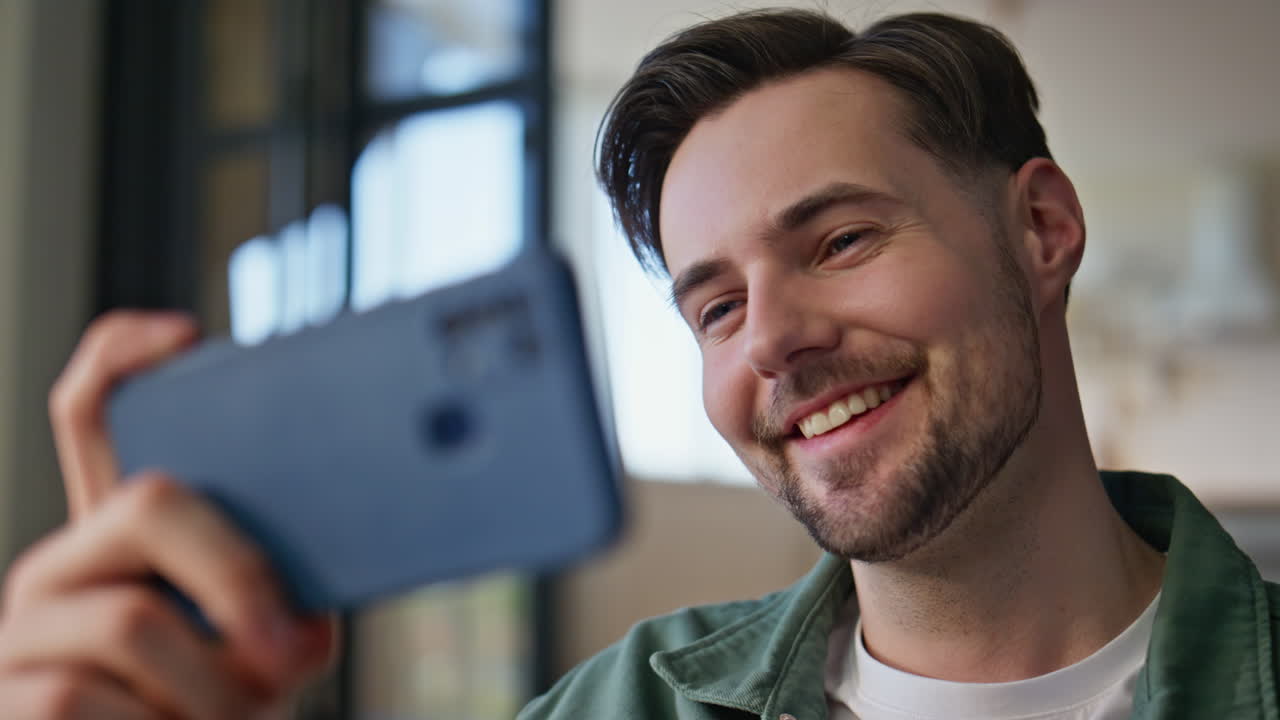 Man hand holding smartphone at light apartment closeup. Guy reading cellphone