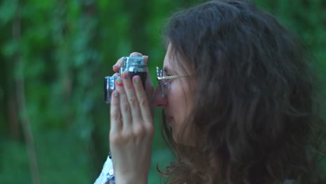 a young woman making pictures outdoors with an old film camera, close up