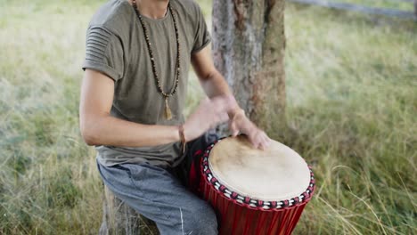 young drummer plays simple african music on a single drum