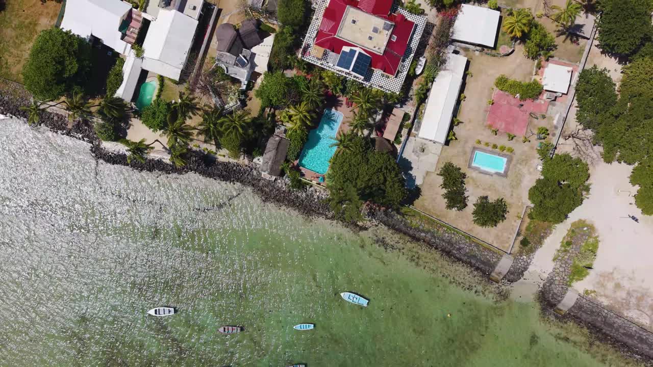 Top-down drone shot of the Mauritius coastline and fringing coral reef. Vibrant turquoise shallows meet the deep blue ocean, highlighting natural patterns and wave breaks