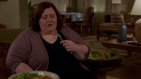 woman makes disgusted faces while eating a salad