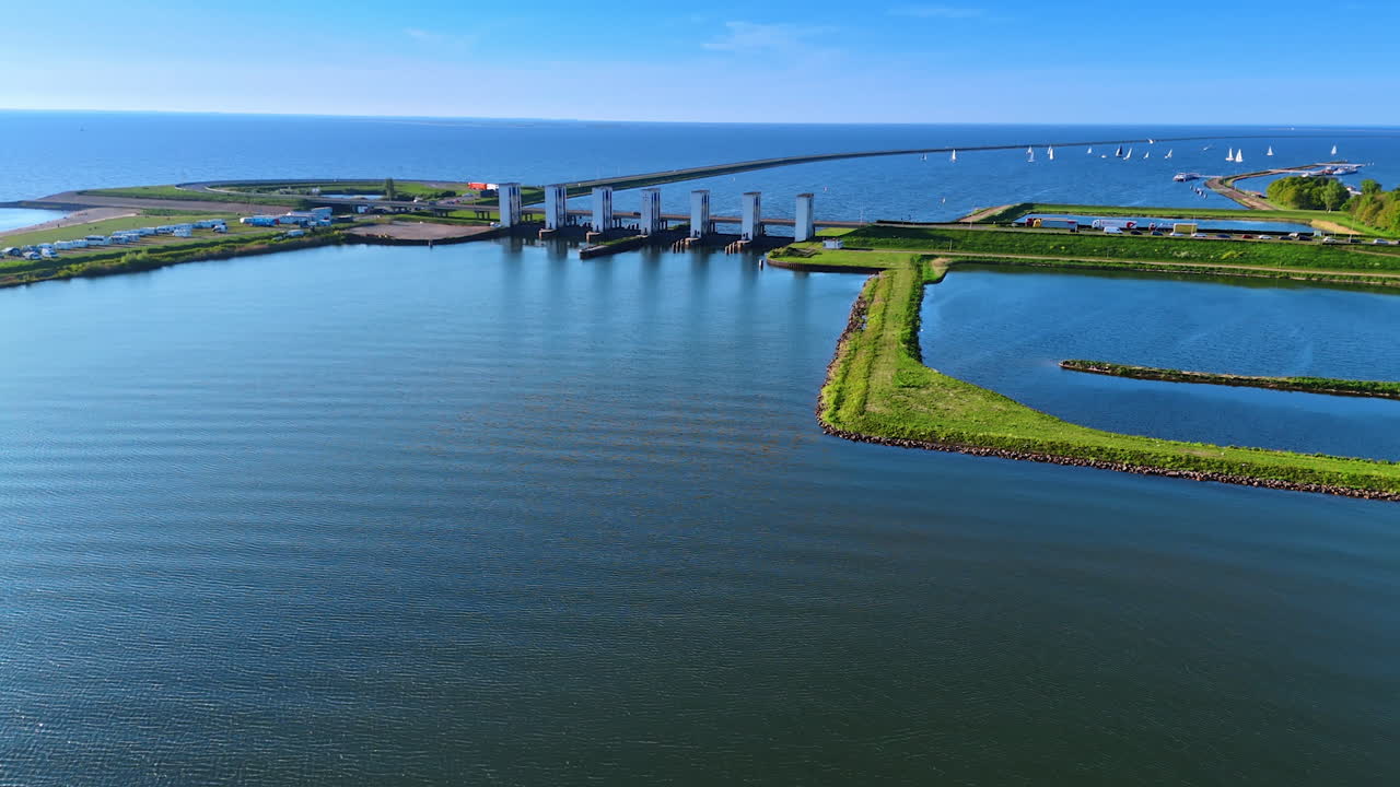 Footage over the peaceful waterscape surrounded by the dikes. Approaching a sluice on the lake in Lelystad, the Netherlands.