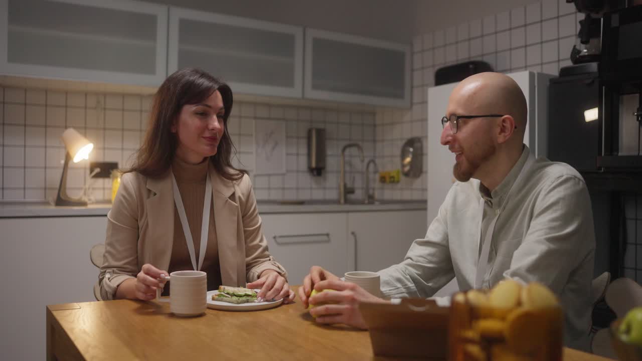Duas pessoas almoçando na cozinha do escritório