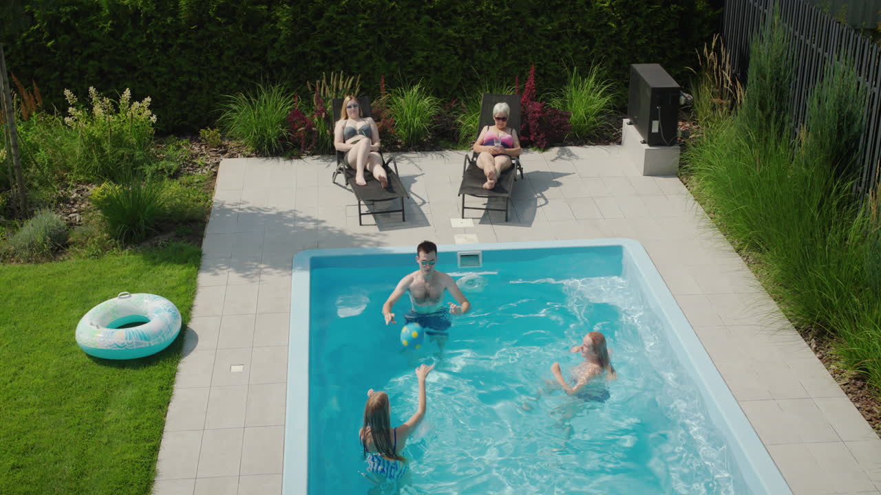 En venlig flergenerationsfamilie slapper af ved poolen på en varm sommerdag.