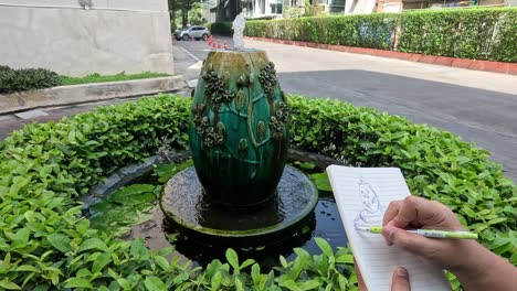 artist drawing a fountain surrounded by greenery.