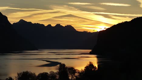 puesta de sol sobre un lago con montañas en el fondo