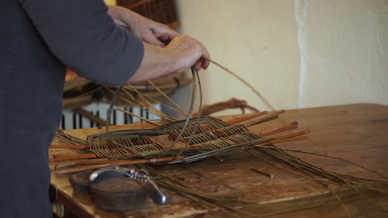 un cestero da forma y teje las varillas de madera mientras hace una cesta galesa tradicional a mano