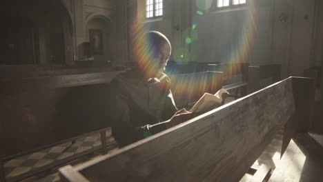 priest sitting on bench and reading in lutheran church