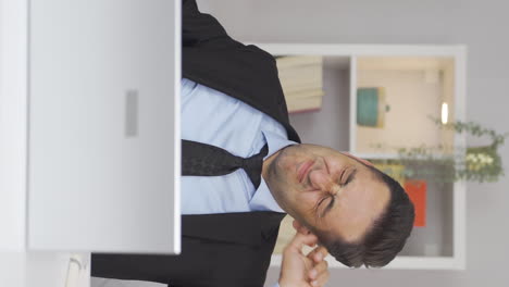 Vertical-video-of-Home-office-worker-man-scratches-his-ears-looking-at-camera.