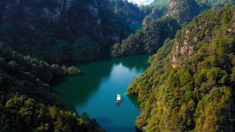 Chinese-boat-floats-peacefully-on-baofeng-lake,-aerial-pullback-zhangjiajie,-Wulingyuan-Hunan-China