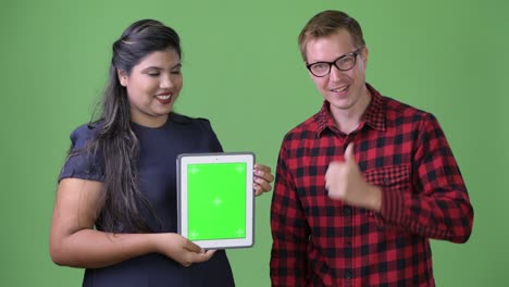 joven pareja de negocios multiétnica juntos contra un fondo verde
