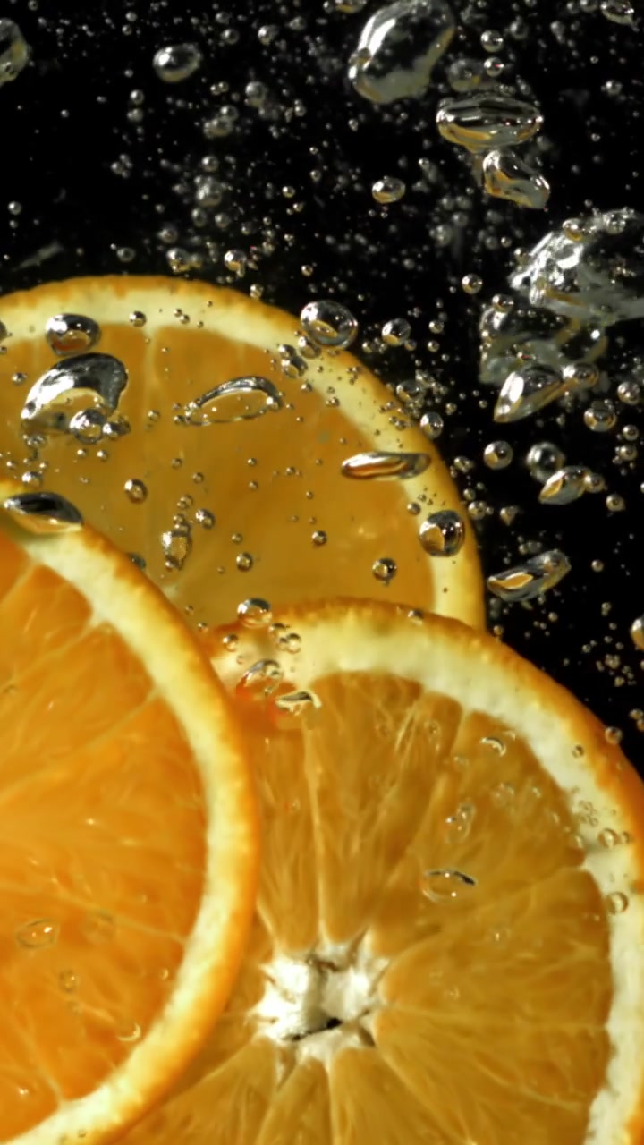 Fette d'arancia vivaci immerse nell'acqua con bolle che salgono