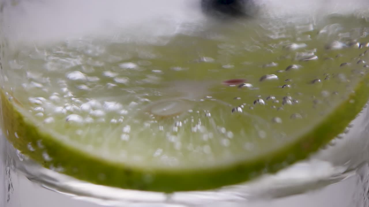 화려한 물에 인 라임 조각의 클로즈업, 거품과 응축을 매크로 뷰에서 강조합니다.