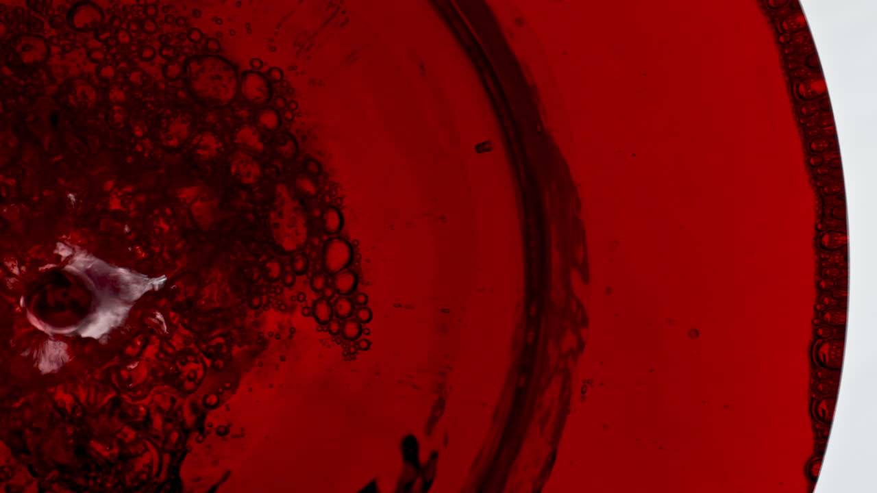 vino rojo de relleno de vaso de primer plano. líquido alcohólico de rosa efervescencia de vidrio de vino macro