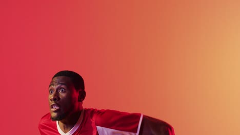 african american male soccer player returning football with head over neon pink lighting