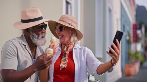 mature couple enjoying ice cream and taking selfies on vacation