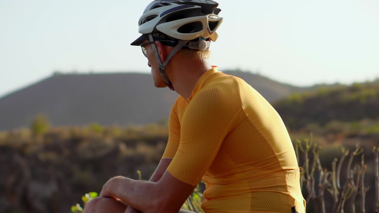 After completing his ride, the man cyclist rests and admires the stunning mountain landscape