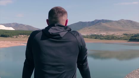 Man-standing-on-a-fence-of-a-dam-sightseeing-the-beautiful-nature-and-the-natural-lake