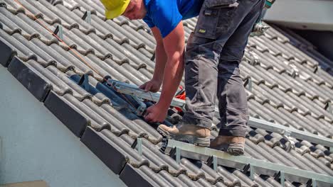 male roof worker stabilizing solar panel construction on sunny day