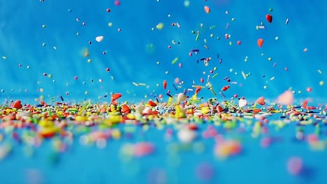 dulces de forma diferente de varios colores están cayendo en una mesa sobre un fondo azul. 4k cámara lenta video divertido brillante.