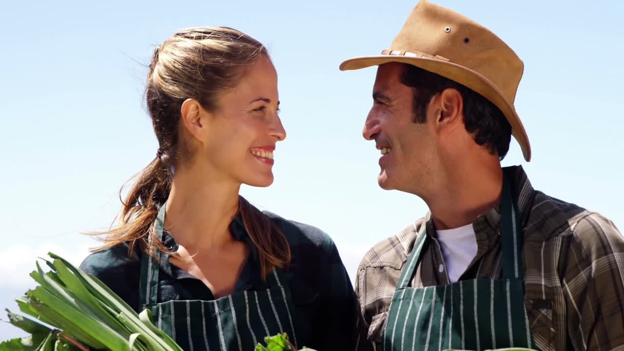 pareja sonriente sosteniendo una remolacha en el campo