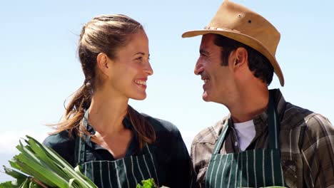 pareja sonriente sosteniendo una remolacha en el campo